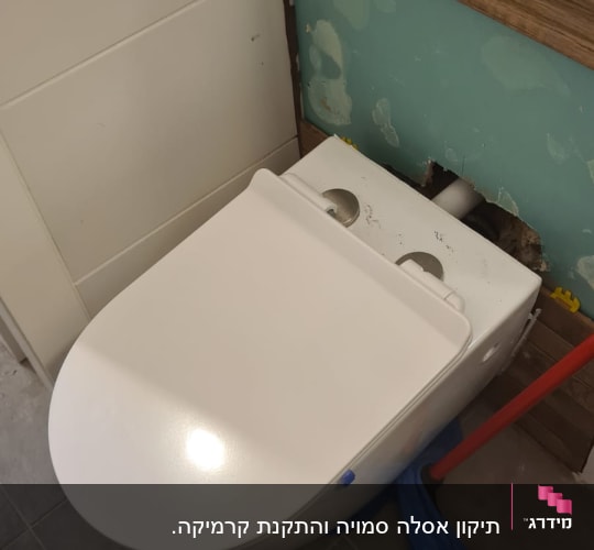 אסלה מותקנת עם מגבת כחולה וכלי עבודה אדום